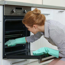 Charger l'image dans la galerie, Femme utilisant des gants de vaisselle en silicone vert pour ouvrir un four dans une cuisine moderne.